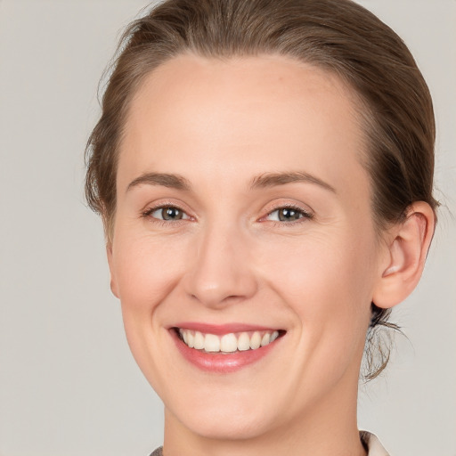 Joyful white young-adult female with medium  brown hair and grey eyes