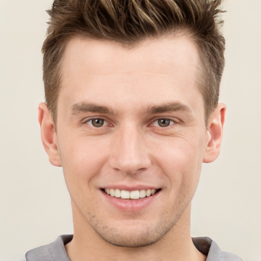 Joyful white young-adult male with short  brown hair and grey eyes