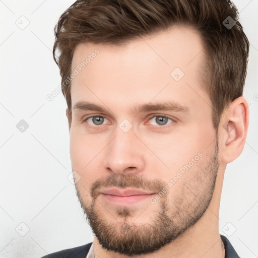 Joyful white young-adult male with short  brown hair and grey eyes