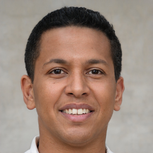 Joyful latino young-adult male with short  brown hair and brown eyes