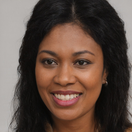 Joyful black young-adult female with long  brown hair and brown eyes
