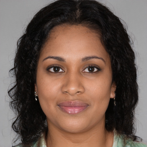 Joyful black young-adult female with long  brown hair and brown eyes
