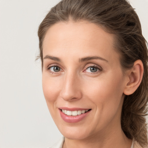 Joyful white young-adult female with medium  brown hair and grey eyes