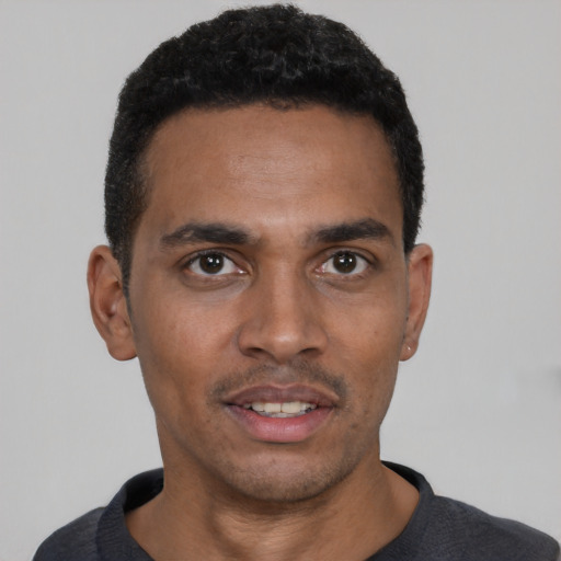 Joyful black young-adult male with short  black hair and brown eyes
