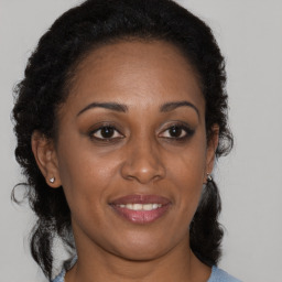 Joyful black young-adult female with long  brown hair and brown eyes