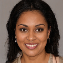 Joyful black young-adult female with long  brown hair and brown eyes