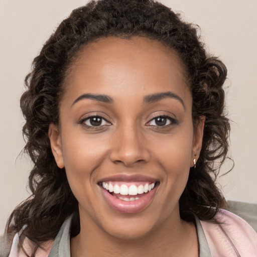 Joyful black young-adult female with long  brown hair and brown eyes