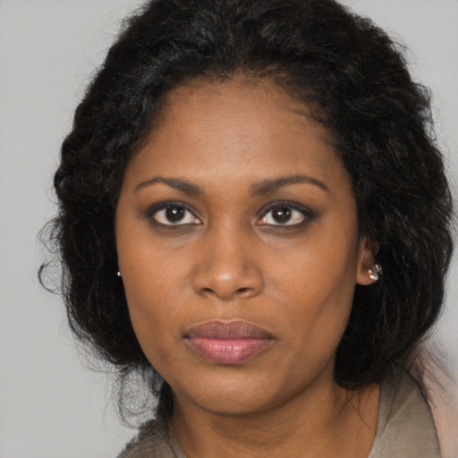 Joyful black young-adult female with long  brown hair and brown eyes