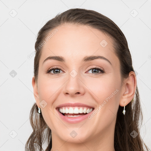 Joyful white young-adult female with long  brown hair and grey eyes