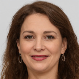 Joyful white adult female with long  brown hair and grey eyes