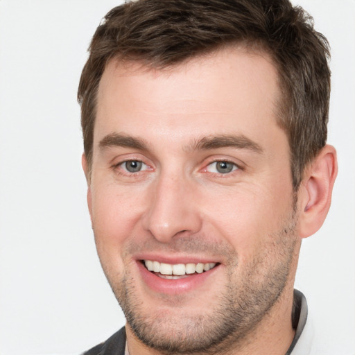 Joyful white young-adult male with short  brown hair and grey eyes