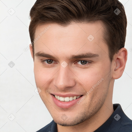 Joyful white young-adult male with short  brown hair and grey eyes