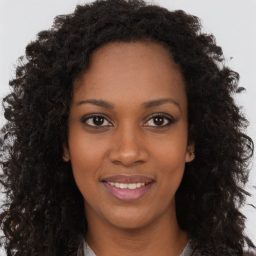 Joyful black young-adult female with long  brown hair and brown eyes