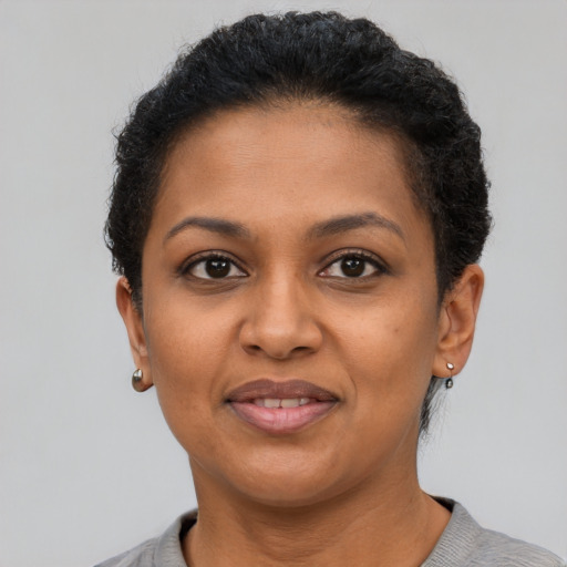 Joyful black young-adult female with short  black hair and brown eyes