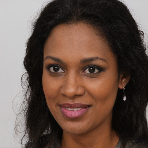 Joyful black young-adult female with long  brown hair and brown eyes