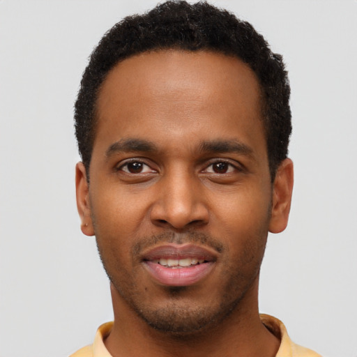 Joyful black young-adult male with short  brown hair and brown eyes