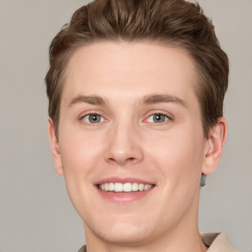 Joyful white young-adult male with short  brown hair and grey eyes