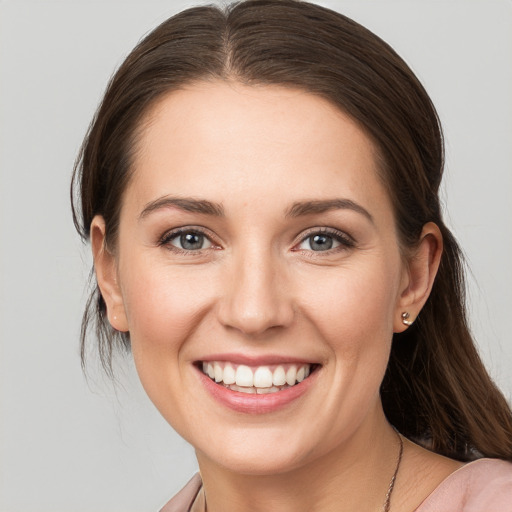 Joyful white young-adult female with medium  brown hair and grey eyes