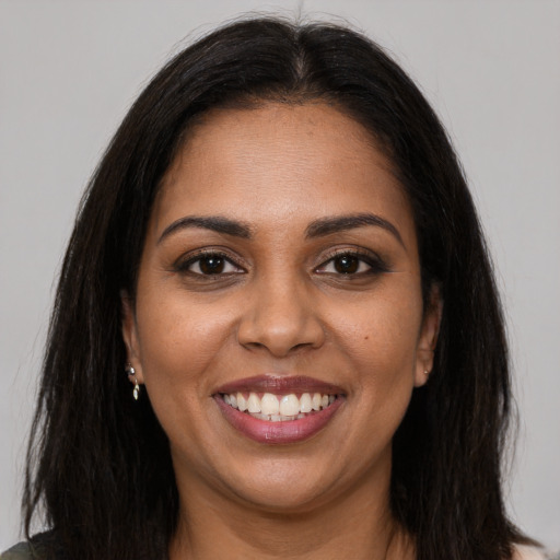 Joyful black young-adult female with long  brown hair and brown eyes