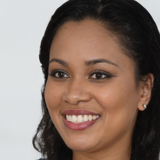 Joyful black young-adult female with long  black hair and brown eyes