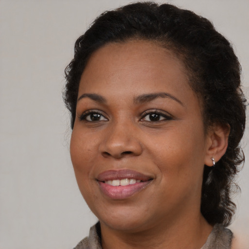Joyful black young-adult female with long  brown hair and brown eyes