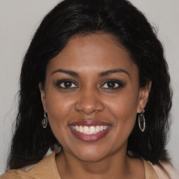 Joyful black young-adult female with long  brown hair and brown eyes