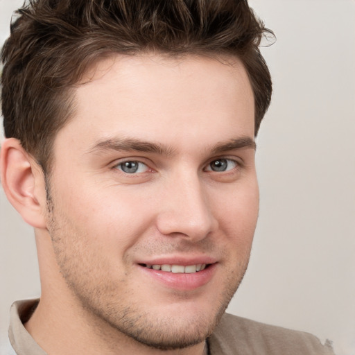 Joyful white young-adult male with short  brown hair and grey eyes