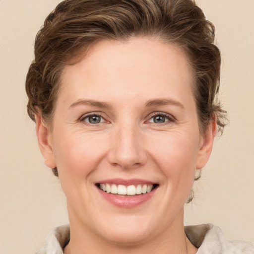 Joyful white young-adult female with short  brown hair and green eyes