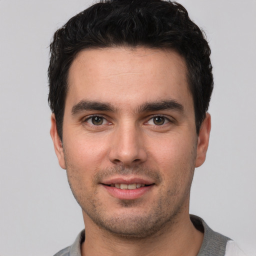 Joyful white young-adult male with short  black hair and brown eyes