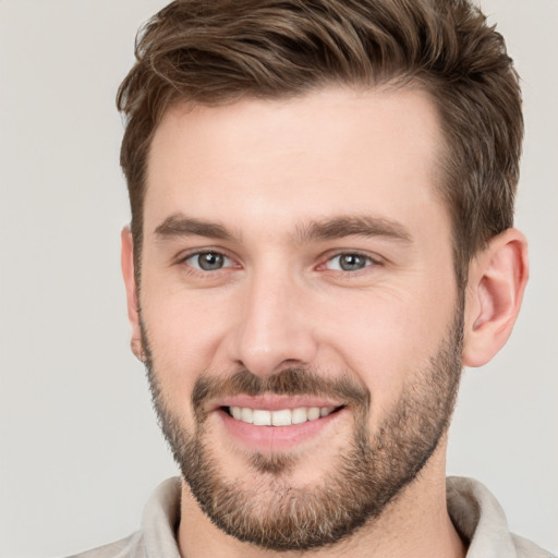 Joyful white young-adult male with short  brown hair and grey eyes