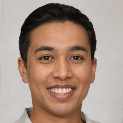 Joyful latino young-adult male with short  black hair and brown eyes