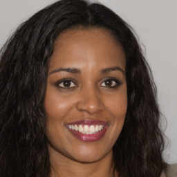 Joyful black young-adult female with long  brown hair and brown eyes