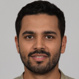 Joyful latino young-adult male with short  black hair and brown eyes