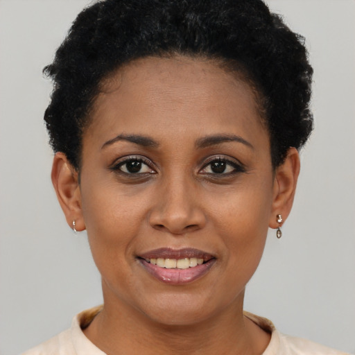 Joyful black young-adult female with short  black hair and brown eyes