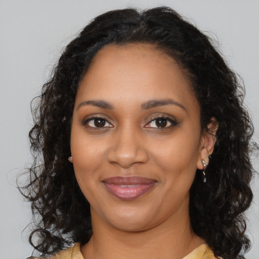 Joyful black young-adult female with long  brown hair and brown eyes