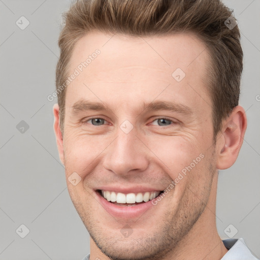 Joyful white young-adult male with short  brown hair and grey eyes