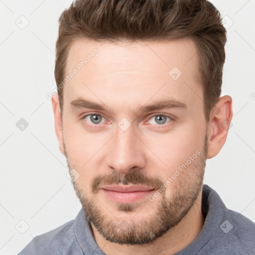 Joyful white young-adult male with short  brown hair and grey eyes