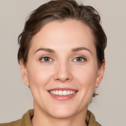 Joyful white young-adult female with medium  brown hair and grey eyes