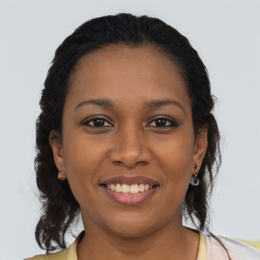 Joyful black young-adult female with long  brown hair and brown eyes