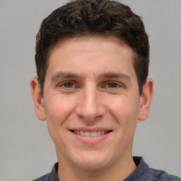 Joyful white young-adult male with short  brown hair and grey eyes