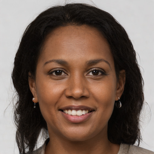 Joyful black young-adult female with long  brown hair and brown eyes