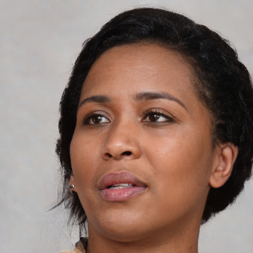 Joyful black young-adult female with short  black hair and brown eyes