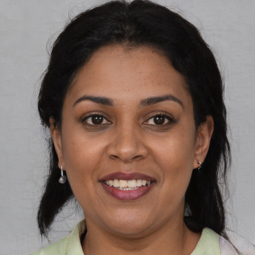 Joyful latino adult female with medium  black hair and brown eyes