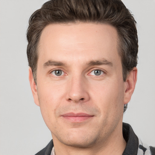 Joyful white young-adult male with short  brown hair and grey eyes