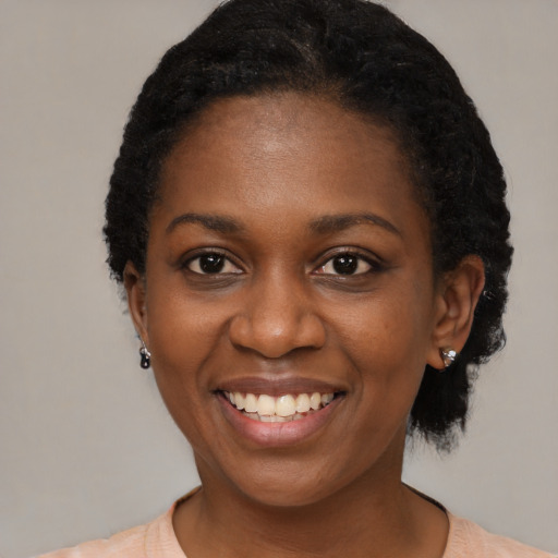 Joyful black young-adult female with short  black hair and brown eyes