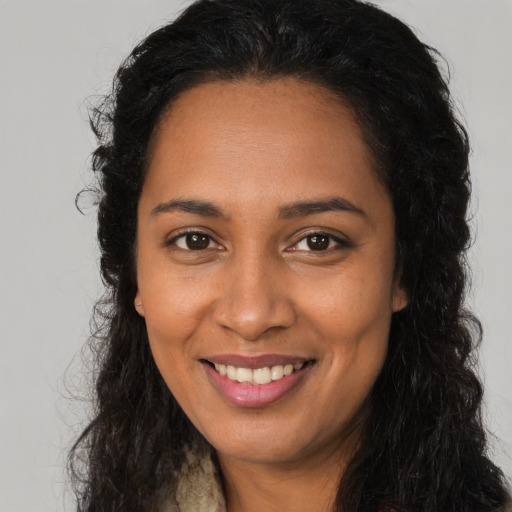 Joyful black young-adult female with long  brown hair and brown eyes