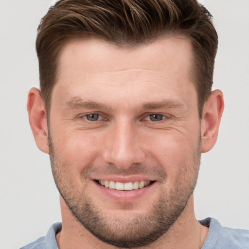 Joyful white young-adult male with short  brown hair and grey eyes