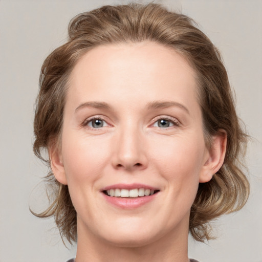 Joyful white young-adult female with medium  brown hair and grey eyes