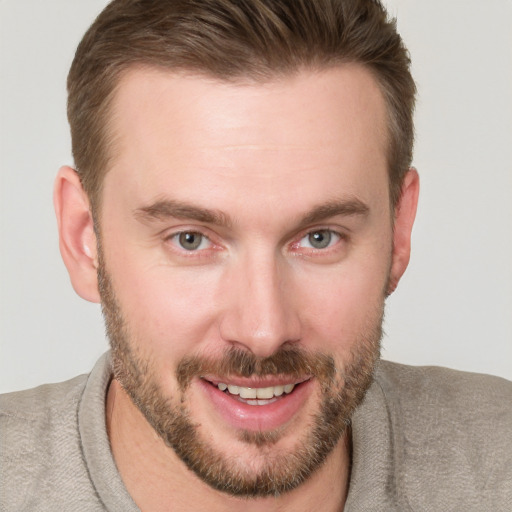 Joyful white young-adult male with short  brown hair and blue eyes