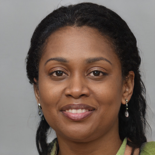 Joyful black young-adult female with long  brown hair and brown eyes